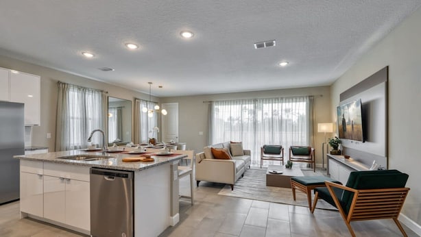 A modern kitchen with a central island, a dining area with a sofa and chairs, and a living room with a TV and seating. - Dream Home Prime Location Themed Bedrooms (Kissimmee)