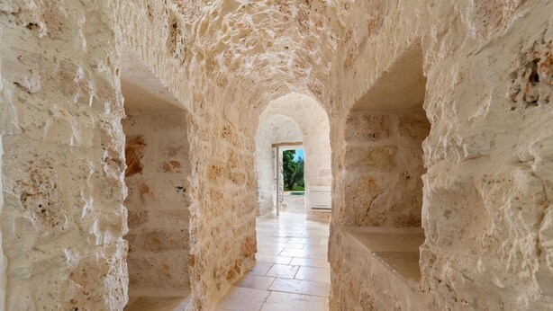 A stone corridor with arched doorways leading to a brighter area. - 3474 Trulli Dafani by Perle di Puglia (Ostuni)