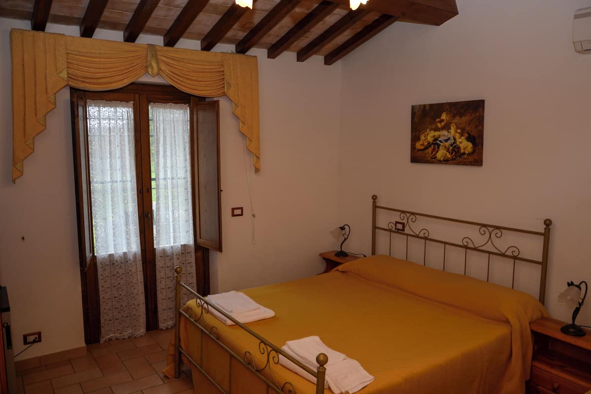 Un dormitorio con cama, cortinas, un cuadro y techo de madera.