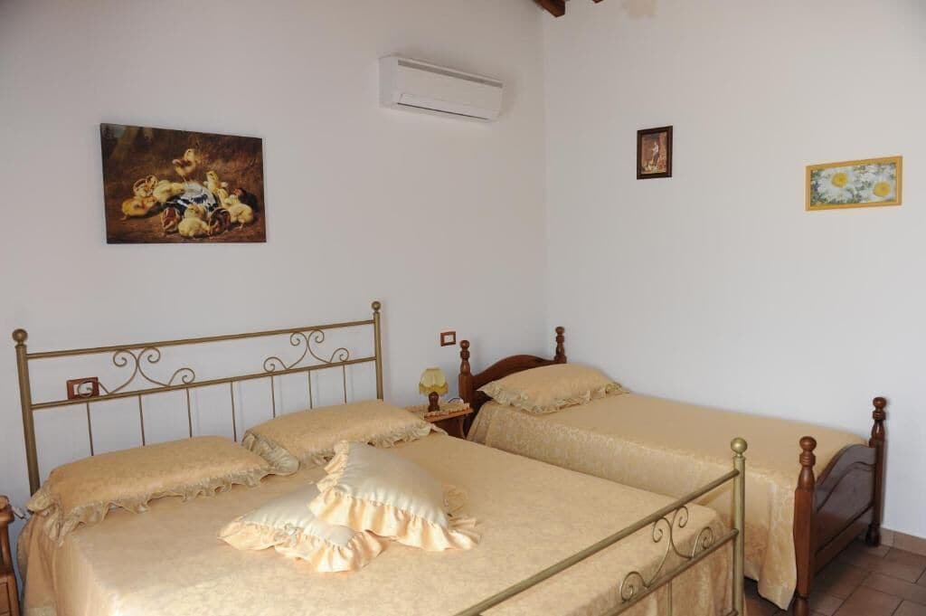 Ein Schlafzimmer mit zwei Einzelbetten, einem Holzkopfstück, einem Nachttisch mit Lampe sowie einem Bild an der Wand.