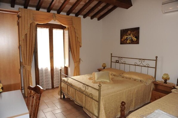 A bedroom with a bed, a chair, a nightstand, and a painting on the wall.