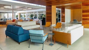 A modern lobby with a wooden ceiling, white sofas, and orange chairs. - Apartment 01 double room (Palhoça)