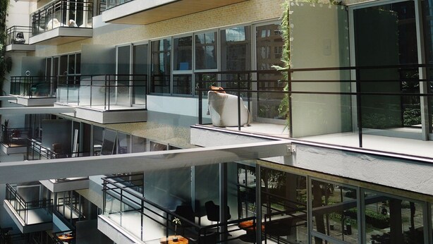 A multi-level building with glass railings, outdoor seating, and a skylight. - Apartment 01 double room (Palhoça)