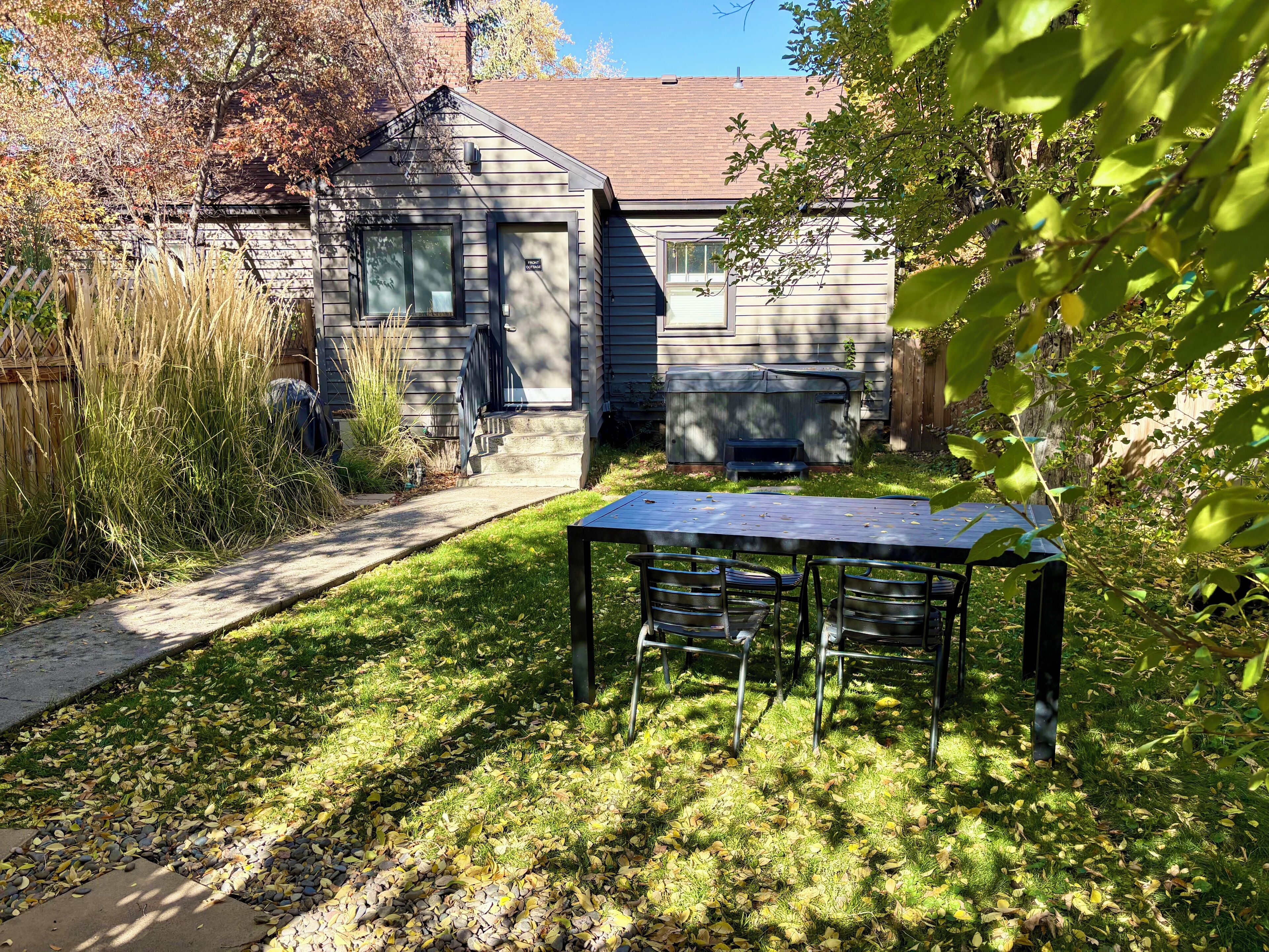 Een achtertuin met een houten terras, een barbecue en een tafel met stoelen.