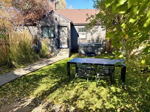 Un jardin avec une terrasse en bois, un barbecue et une table avec des chaises.