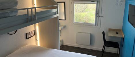 Habitación con literas, una ventana, escritorio y silla.
