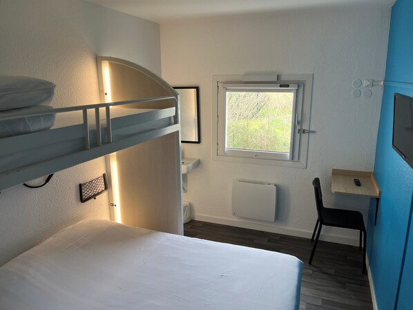 Habitación con literas, una ventana, escritorio y silla.