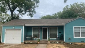 A single-story house with a garage, a front porch with potted plants, and a mailbox. - 3 blocks from AT&T Stadium 2 bedroom-sleeps 6 (Arlington)