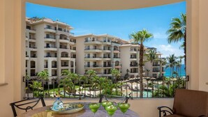 Un balcon avec vue sur un bâtiment d’hôtel, une piscine et des palmiers.