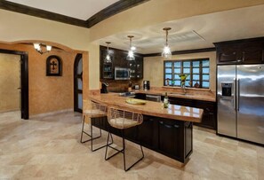 Uma cozinha moderna com uma ilha grande, banquetas, eletrodomésticos de aço inoxidável e vista pela janela.