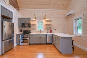 A modern kitchen with grey cabinets, stainless steel appliances, and a wooden floor.
