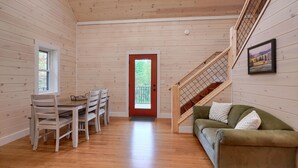 Un interior de madera con una zona de comedor, un sofá y una escalera.