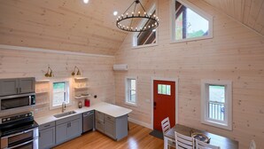 Una cocina moderna con una isla central, electrodomésticos integrados y un comedor con una puerta roja.