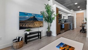 A modern kitchen with stainless steel appliances, a dining area with a bench, and a large painting on the wall. - Best Amenities Pool/Htub/Gym/Pking Downtown Views! (Salt Lake City)