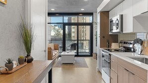 A modern kitchen with a large window, a dining area with a sofa, and a view of the city. - Best Amenities Pool/Htub/Gym/Pking Downtown Views! (Salt Lake City)