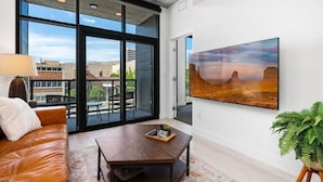 Ein modernes Wohnzimmer mit einer Ledersofa, einem Couchtisch und einem großen Fenster mit Blick auf die Stadt.