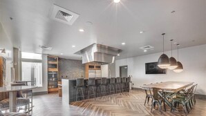 A modern kitchen with a central island, bar stools, and a dining table with chairs. - Penthouse Apt - PoolGymHotTubPkg - View! (Salt Lake City)