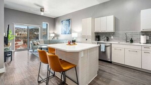 A modern kitchen with a central island, bar stools, and a dining area with a view. - Penthouse Apt - PoolGymHotTubPkg - View! (Salt Lake City)