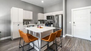 A modern kitchen with white cabinets, stainless steel appliances, and a central island with two chairs. - Penthouse Apt - PoolGymHotTubPkg - View! (Salt Lake City)