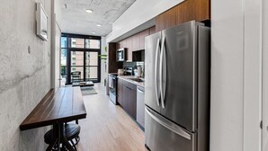 Una cocina moderna con electrodomésticos de acero inoxidable, una mesa de comedor de madera y vistas a través de la puerta de vidrio.