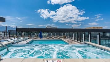 Piscina no terraço com placa indicando limite de profundidade de 1 metro e 0,03 metro, cadeiras de descanso e vista clara das montanhas ao fundo.