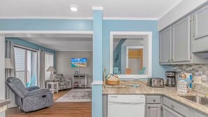 A modern kitchen with grey cabinets, a dishwasher, and a countertop with a toaster and coffee maker. - Sea Turtle (Myrtle Beach)