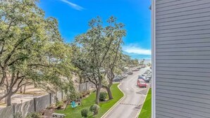 A residential street with parked cars, trees, and a clear blue sky. - Sea Turtle (Myrtle Beach)