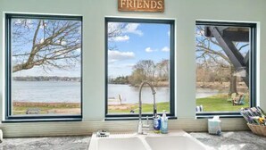 Une salle de bain avec une grande fenêtre, un lavabo et une affiche « FRIENDS » au-dessus.