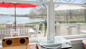 Une chambre avec vue sur un lac, un parapluie rouge et une table avec un haut-parleur.