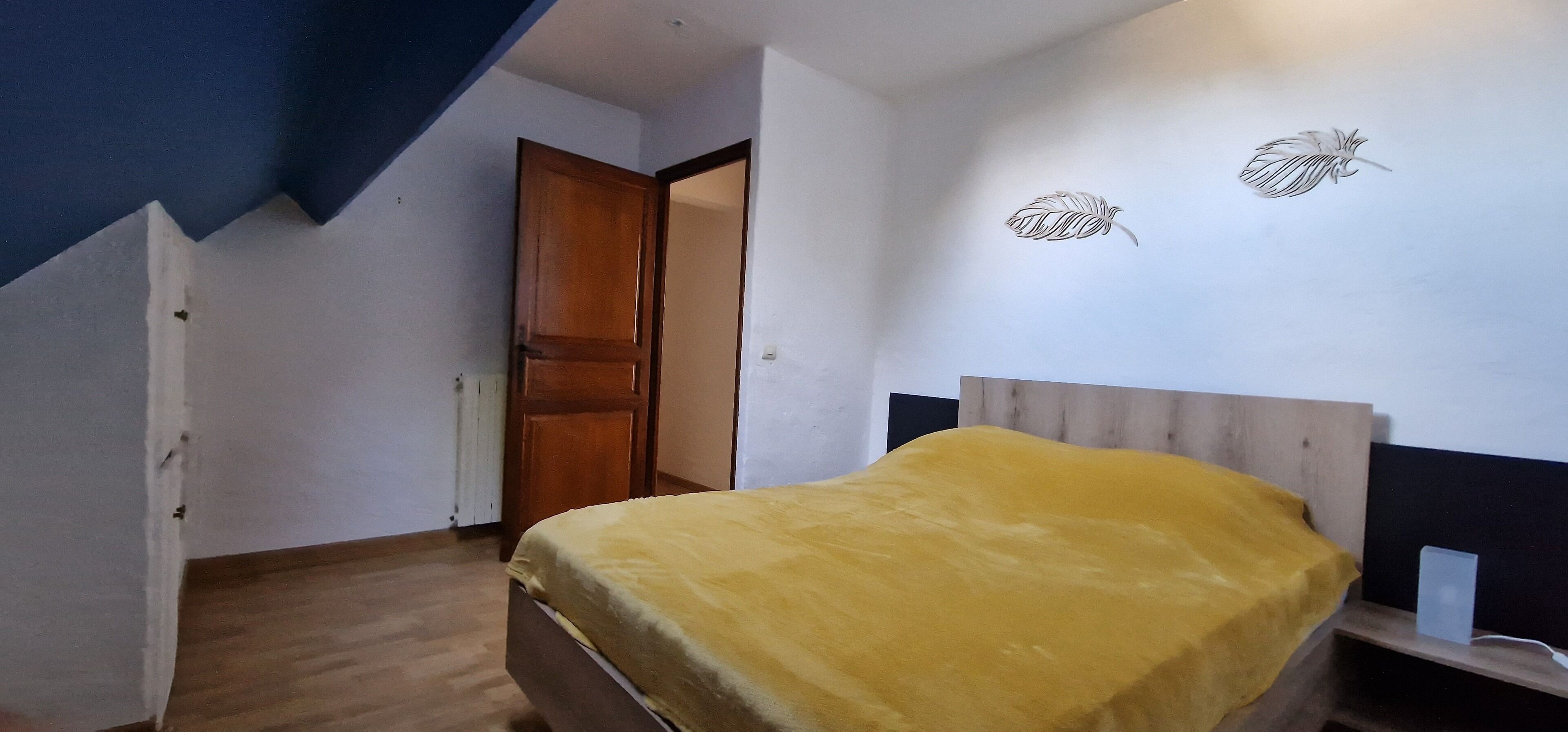 Een slaapkamer met een bed, een houten deur en een muur met twee bladdecoraties.