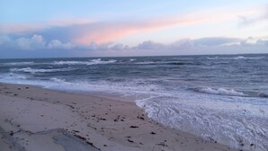 Een strand met golven die op het strand breken en een heldere lucht.