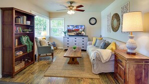 Ein Wohnzimmer mit einer Couch, einem Couchtisch, einem Bücherregal und einem Deckenventilator.