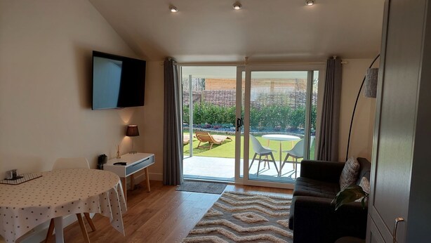 A modern living room with a dining table, sofa, and TV. - Holly -  a dunley cottages - devon that sleeps 2 guests  in 1 bedroom (Bovey Tracey)