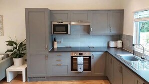 A modern kitchen with grey cabinets, a microwave, a built-in oven, and a sink. - Holly -  a dunley cottages - devon that sleeps 2 guests  in 1 bedroom (Bovey Tracey)