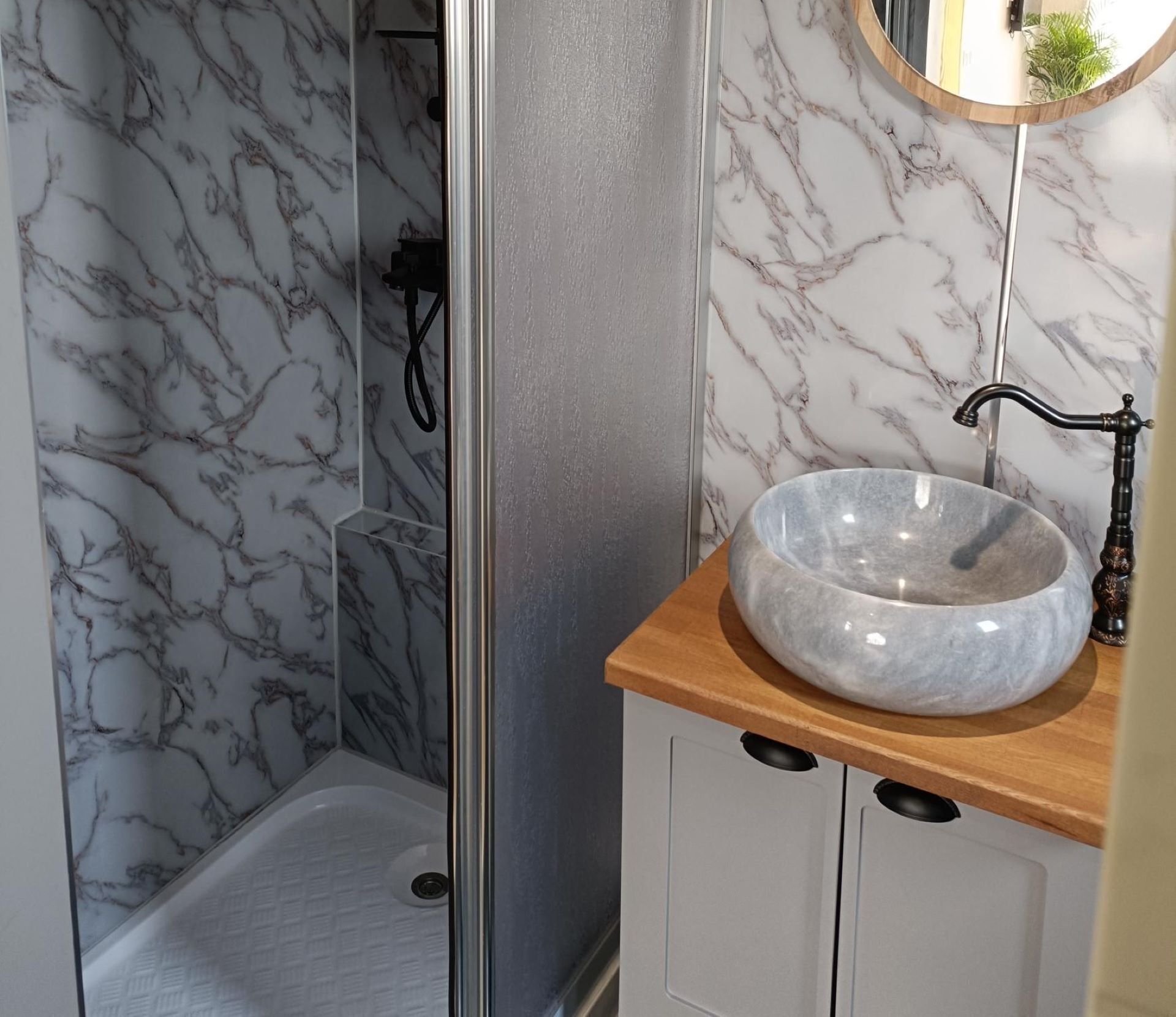 Een badkamer met marmeren wanden, een houten wastafelmeubel en een moderne wastafel.
