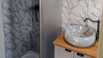 Een badkamer met marmeren wanden, een houten wastafelmeubel en een moderne wastafel.
