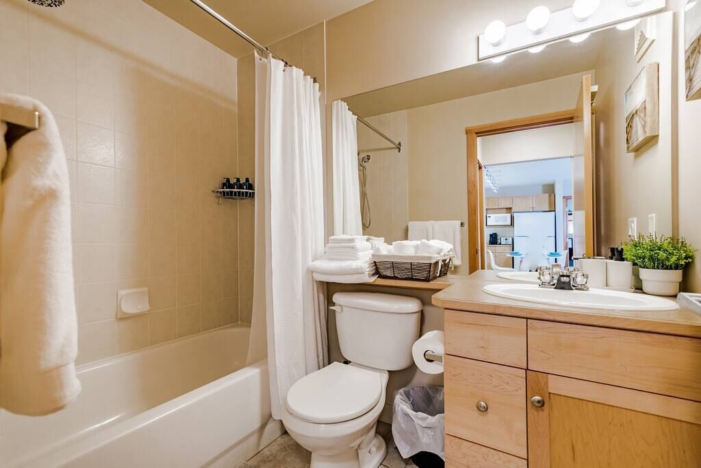 A bathroom with a bathtub, toilet, vanity with a mirror, and a shower curtain.