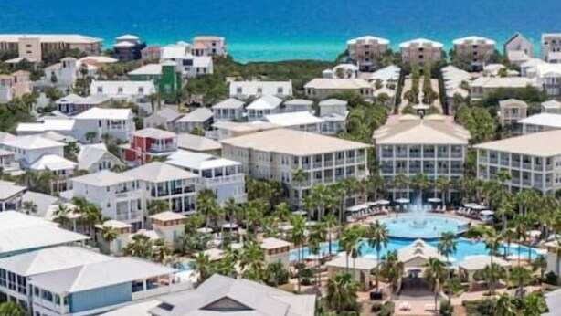 Un resort con varias construcciones, una piscina central y vista al océano.