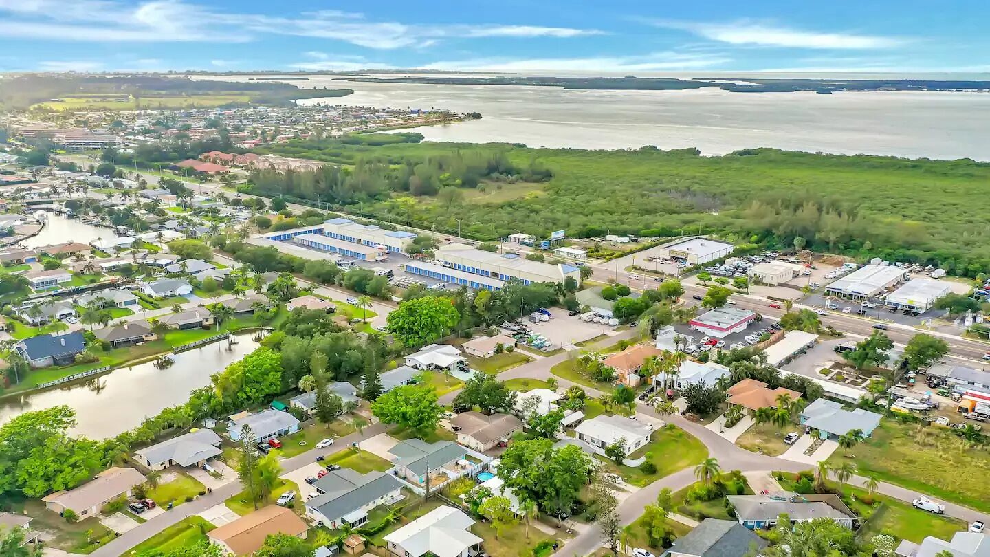 An aerial view of a residential area with houses, a large building complex, and a river.