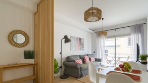 A modern living room with a grey sofa, white chairs, a dining table with fruit, and a large window with curtains. - Pascal Home By CanariasGetaway (Las Palmas de Gran Canaria)