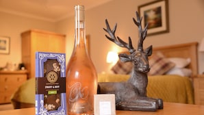A bottle of chocolate, a box of chocolate, and a deer figurine on a table. - Lochview Guest House (Fort William)