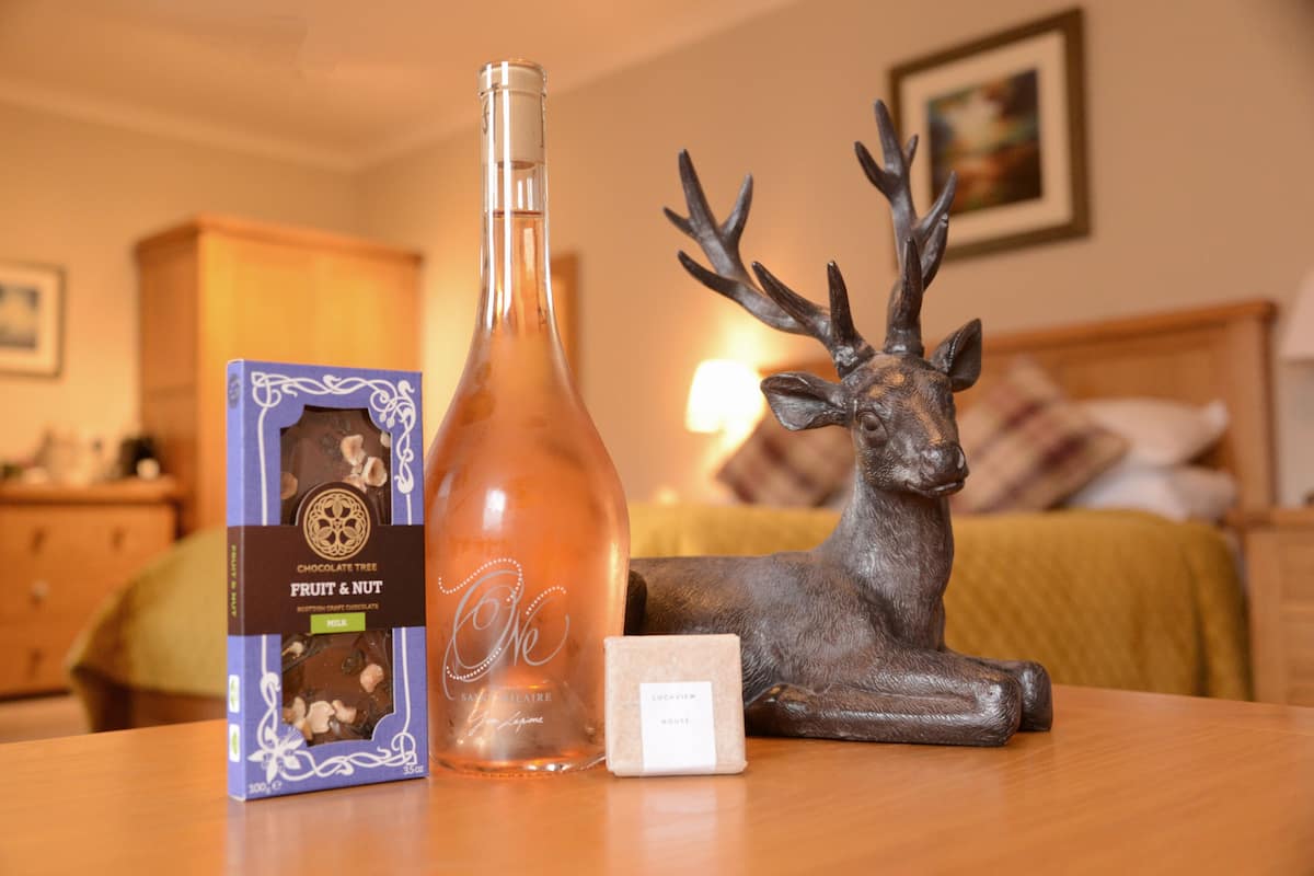 A bottle of chocolate, a box of chocolate, and a deer figurine on a table.