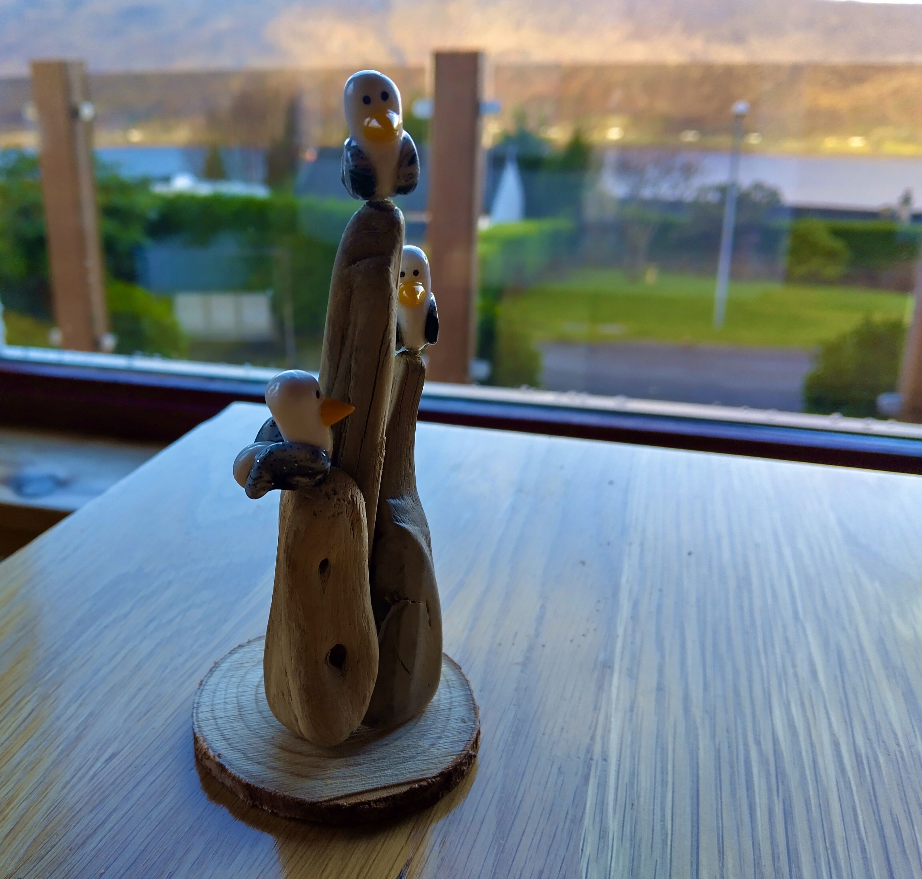 Una escultura de madera con pájaros sobre una base redonda de madera.
