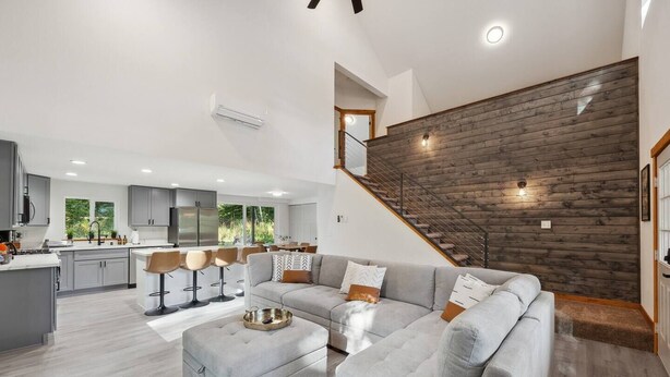 Ein modernes Wohnzimmer mit einem grauen Ecksofa, einem Couchtisch und einer Treppe mit Holzvertäfelung.