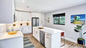 A modern kitchen with white cabinetry, stainless steel appliances, and a central island.