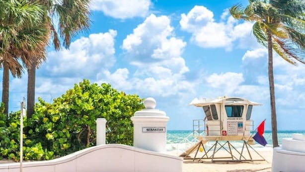 A lifeguard tower named "Sebastian" on a beach with palm trees and ocean views.