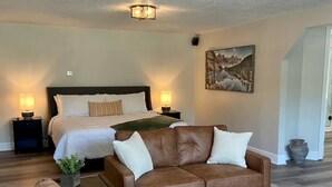 A spacious living room with a large brown sofa, a coffee table, and a bed with a headboard in the background. - Hidden Gem Modern Loft (Mission)