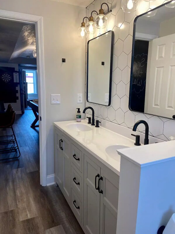 A modern bathroom with a double sink, a large mirror, and a hexagonal tile backsplash. - Hidden Gem Modern Loft (Mission)
