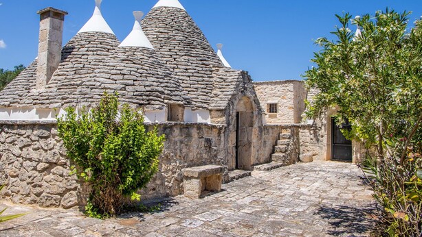 A stone building with a sloped roof and a chimney. - 3598 Trullo Yoram by Perle di Puglia (Francavilla Fontana)