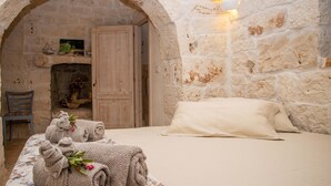 A cozy room with a bed, a wooden door, and a stone wall. - 3598 Trullo Yoram by Perle di Puglia (Francavilla Fontana)